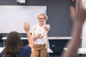 Teacher points at students raising their hands