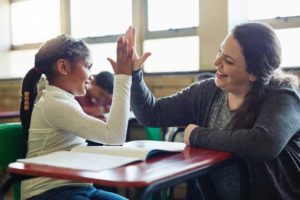 Teacher does high five with a young girl student