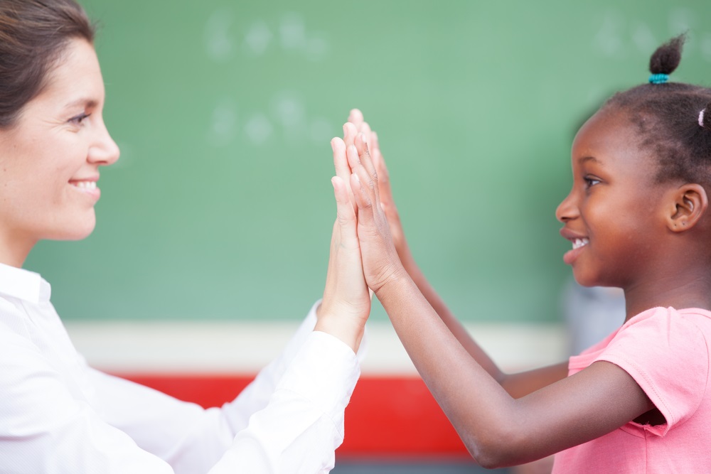 african schoolgirl and female teacher doing high five after math lesson