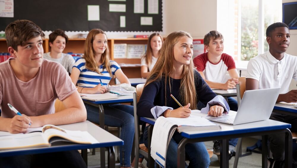 students listening to female teacher in classroom