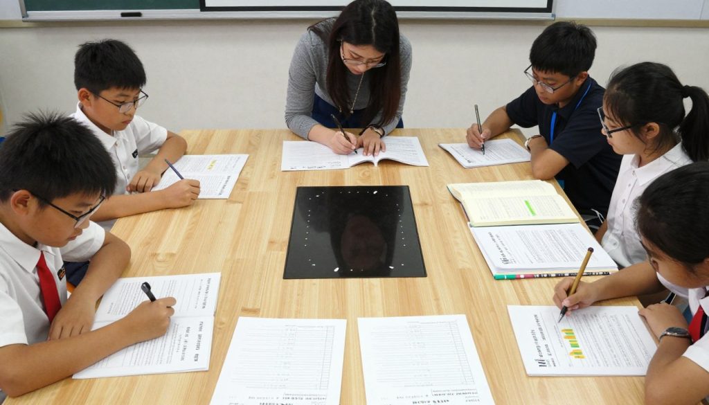 Classroom with students working on tiered assignments at different levels Classroom with students working on tiered assignments at different levels